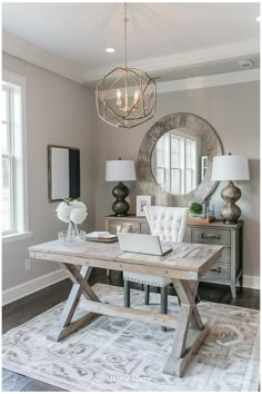 a dining room table with a laptop on it and a chandelier hanging from the ceiling