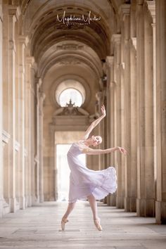 a young ballerina is posing in an old building with columns and arches on the floor