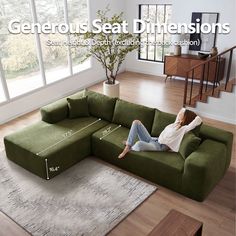 a woman sitting on top of a green couch in a living room next to a window