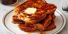 a stack of french toast with butter and syrup on a white plate next to a fork