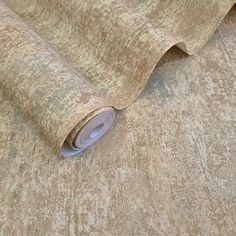 a roll of fabric on top of a bed covered in brown and beige wallpaper