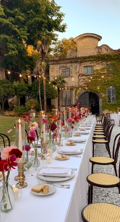 a long table is set up with flowers and candles for an outdoor dinner or party