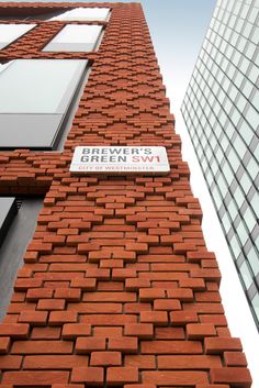 a red brick building with a street sign on it's side in front of tall buildings