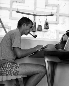 a man sitting at a desk with a pipe in his mouth