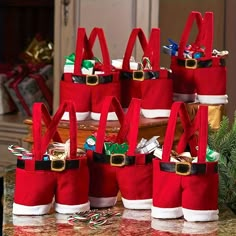 several red bags with santa's hats on them sitting on a table next to christmas decorations