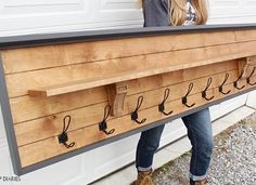 a woman holding up a wooden sign with hooks on it