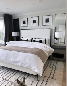 a white bed sitting in a bedroom next to a window with pictures on the wall