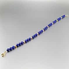 Classic bracelet with blue Lapis Lazuli polished beads and 14K gold plated beads and clasp. Unique gift for her, girlfriend, mom, sister, friendship stone gift, September and December birthstone, 9 year anniversary. The stones are arranged symmetrically with the precious metal parts. The stones are strung on stainless steel and finished with a Sterling silver 3 times 14K gold plated clasp. All our stones are natural stones and our jewelry handmade, slight differences in color and shape may occur Blue Beaded 14k Gold-filled Jewelry, Elegant Adjustable Blue Gold Bracelet, Elegant Blue Adjustable Gold Bracelet, Hand-strung Gold Lapis Lazuli Bracelets, 14k Gold Bracelet With Polished Beads As A Gift, Gold Bracelets With Lapis Lazuli And Natural Stones, Beaded Bracelets With Natural Stones In Gold, Blue Polished Beads Bracelets For Gift, 14k Gold Beaded Bracelets With Polished Beads As Gift