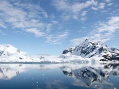 the mountains are covered in snow and ice as they reflect on the water's surface