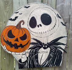 a painted pumpkin and jack skellingy face on a wooden fence