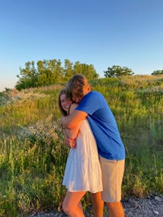 two people hugging each other in the grass