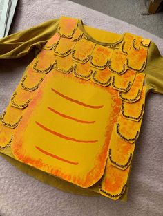 a child's paper costume made to look like an orange and yellow dragon head