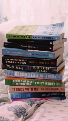 a stack of books sitting on top of a bed