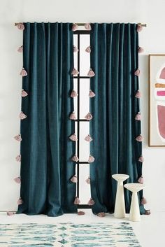 a living room with blue curtains and a rug in front of the window that has tassels on it