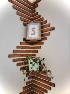 a wooden shelf with a clock on top of it and some plants in the bottom