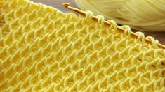 a close up view of a yellow knitted blanket with yarn in the background and a ball of yarn on the floor