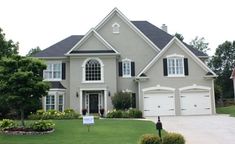 a house with a for sale sign in front of it and landscaping around the driveway