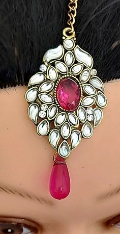 a close up of a woman's head wearing a red and white brooch