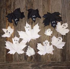 some fake leaves with faces and eyes on them are sitting on a wooden surface in the shape of bats