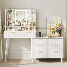 a white dresser and mirror in a room next to a window with flowers on it