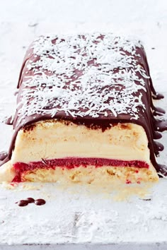 a piece of cake with chocolate and raspberry filling on the top, sitting on a white surface