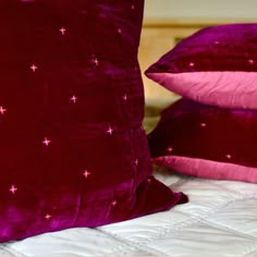 two red pillows sitting on top of a bed