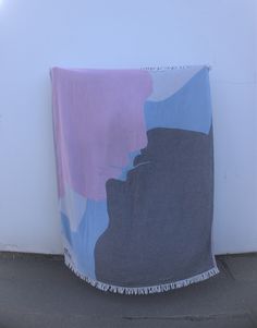 a blanket sitting on the ground next to a white wall with a purple and blue design