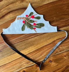 a pair of scissors are laying on top of a piece of fabric that is decorated with leaves and berries