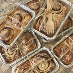 several trays of cinnamon rolls tied with twine and sitting on top of a table