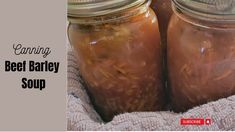 two jars filled with beef barley soup sitting on top of a towel next to each other