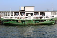 a large green and white boat floating on top of the ocean next to a building