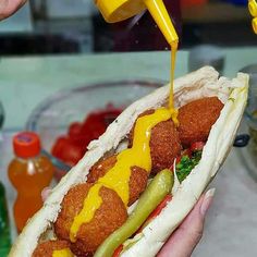 someone is pouring mustard on a hot dog