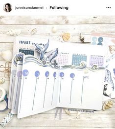 an open planner book sitting on top of a wooden table next to seashells