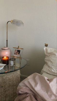 a glass table topped with a pink vase next to a bed