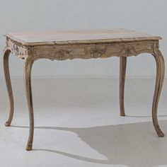 an old wooden table sitting on top of a white floor next to a gray wall