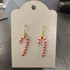 pair of red and white beaded earrings sitting on top of a wooden table next to a card