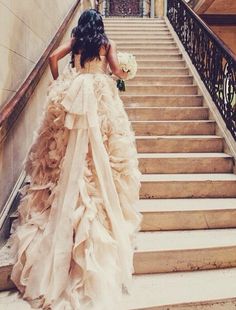 a woman in a wedding dress walking down some stairs