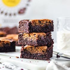 chocolate brownies stacked on top of each other with a glass of milk in the background