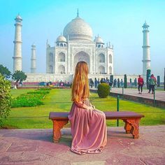 a woman sitting on a bench in front of the tajwa mosque, india