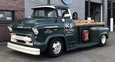 an old green truck parked in front of a building