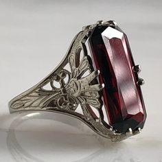 Details: Stunning Edwardian Period garnet and 14K white gold filigree ring! The stone measures 14.5mm by 7mm, and the is 4.6mm above the finger at the highest point on the ring. The filigree is beautiful on this ring, and is in lovely shape. This is a stunning ring--you will not be disappointed! Please ask all necessary questions prior to placing an order. Measurements: The size is 4 1/2 US and can be sized for a fee. Condition: The overall all condition of this ring is very good. Antique Ruby Ring With Filigree For Anniversary, Vintage Garnet Ruby Ring With Intricate Design, Vintage Ruby Ring With Filigree For Formal Events, Classic Engraved Ruby Ring For Formal Occasions, Victorian Ruby Ring With Intricate Design For Formal Events, Vintage Filigree Ring With Gemstone For Formal Events, Victorian Engraved Filigree Ring For Formal Occasions, Ornate Ruby Ring With Filigree, Formal Silver Ruby Ring With Engraving