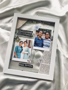 a photo frame with two people on it sitting on a white sheet, and the words happy birthday written in cursive