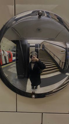 a woman taking a selfie in front of a mirror on the wall next to an escalator