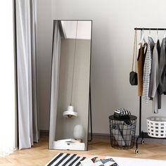 a mirror sitting on top of a hard wood floor next to a white rug and clothes rack