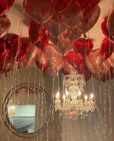 a chandelier hanging from the ceiling filled with red heart shaped balloons