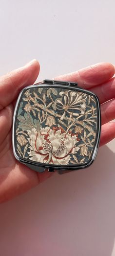 This William Morris print of his famous Honeysuckle and Tulip vintage pattern looks great on this lightweight compact mirror. This handbag mirror would make an ideal bridesmaid gift, birthday present, Christmas stocking filler and more. ABOUT THIS ART NOUVEAU MIRROR COMPACT: * This vintage pocket mirror includes two standard mirrors * Snap enclosure * Vintage William Morris art (reproduction) on the front * Size: 6.7 x 7.5cm * Lightweight compact * Shipped with eco-friendly 100% plastic-free pac William Morris Honeysuckle, Art Nouveau Mirror, Nouveau Mirror, Eclectic Necklace, Compact Art, Bead Accessories, Morris Print, Accessories Craft, Vintage Compact