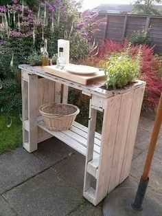 a table made out of pallet wood with plants on top and a basket under it