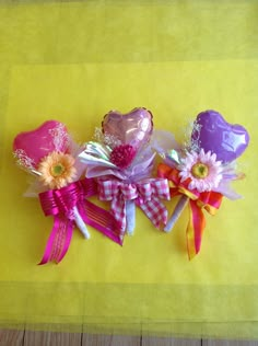 three heart shaped balloons with bows and flowers on a yellow tableclothed cloth background