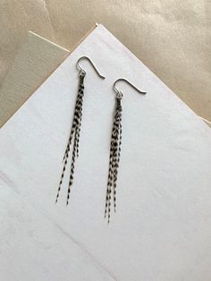 Black and White Grizzly Real Feather Earrings on Stainless Steel Ear Wire Hooks and Silver Colored Finding  Size: 4 inches Available in different lengths in other listings! Stainless Steel Ear Wire Hooks, Nickel and Lead Free, Hypoallergenic.  Each pair of Earrings is Handmade. No two earrings are exactly alike. Earring may have slight imperfection. Length may very.  Shop Info: All Items are Final Sale. No Returns. No Exchanges. If you have any problems with you order please reach out.  All of our pieces are already made and are ready to ship out 24 - 48 Hours after order is placed. We do not ship on Sundays.  All US orders over $35 quality for Free Shipping. We ship most orders using USPS First Class and USPS Ground Advantage. Two Earrings, Boho Accessories, Earrings Black, Accessories Handmade, Feather Earrings, Ear Wire, Final Sale, 4 Inch, Dangle Drop Earrings