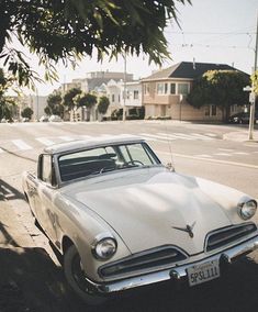 an old car is parked on the side of the road